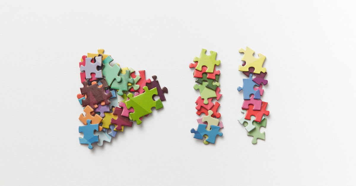 Stacked colorful puzzle pieces on a minimalist white background offering clean copy space.